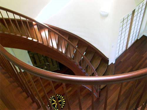 The graceful swooping curves of the railing and custom staircase complement each other nicely in this soaring two-story entry space. Note the shoji (Japanese sliding rice paper) doors, and the splash of natural sunlight falling on the stairs.